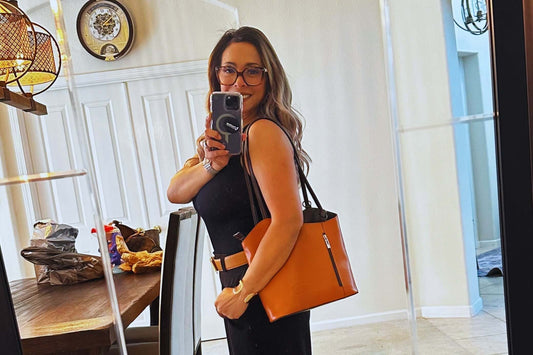 Sweet Caroline showing off the Zaino Convertible Bag in rich cognac leather while taking a mirror selfie.