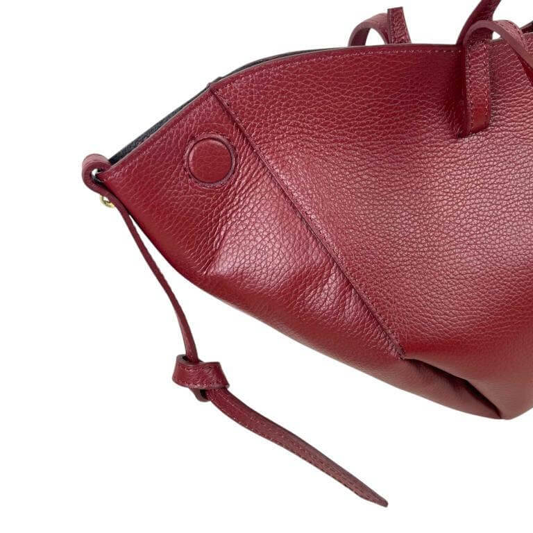 Elegant Italian leather handbag in deep burgundy showcasing its magnetic closure and unique design features.